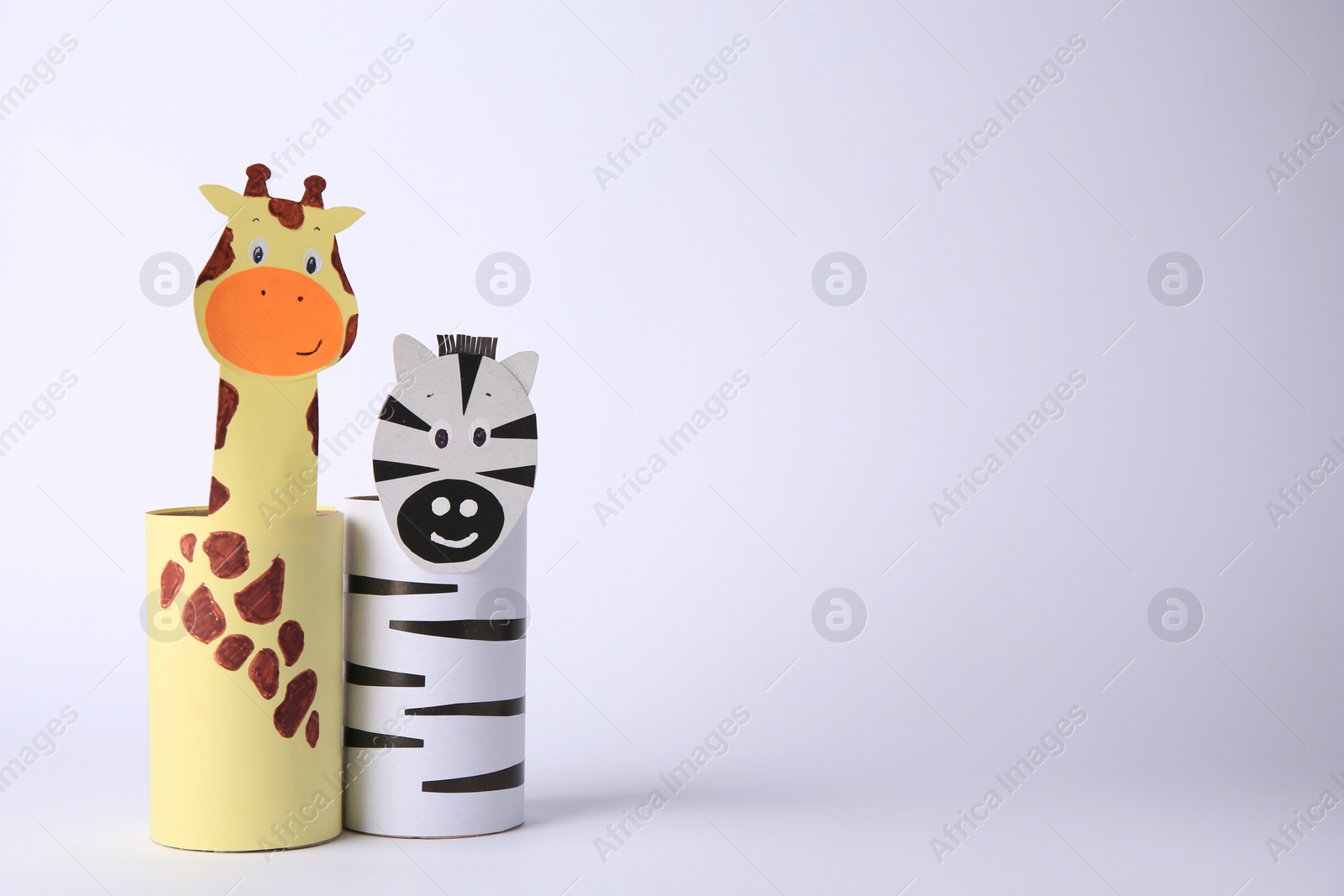 Photo of Toy giraffe and zebra made from toilet paper hubs on white background, space for text. Children's handmade ideas