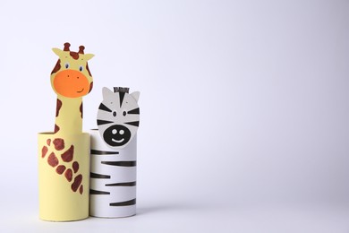 Photo of Toy giraffe and zebra made from toilet paper hubs on white background, space for text. Children's handmade ideas