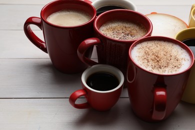 Photo of Many different cups with aromatic hot coffee on white wooden table