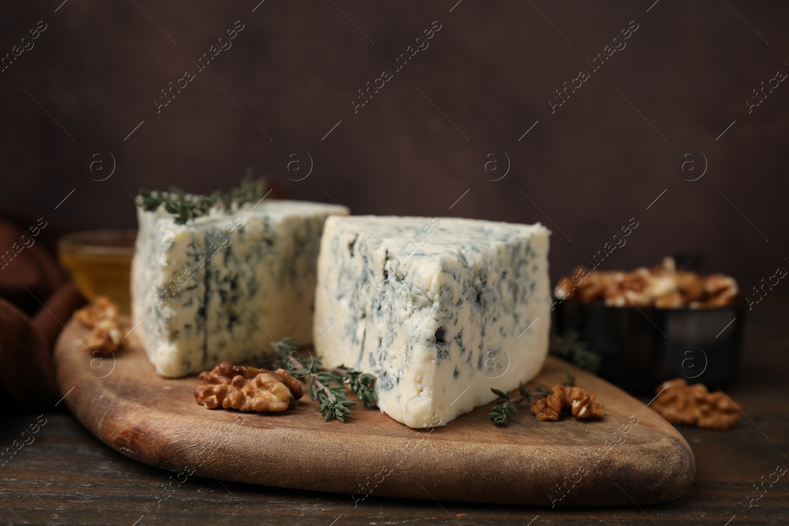 Photo of Tasty blue cheese with thyme and walnuts on wooden table, closeup