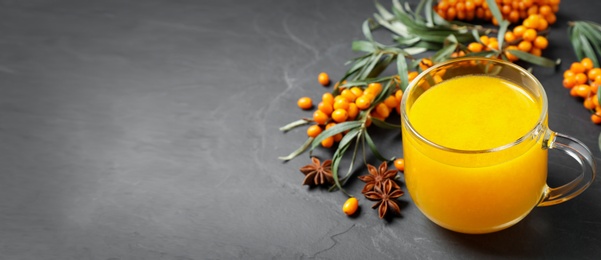 Image of Sea buckthorn tea and fresh berries on grey table, space for text. Banner design