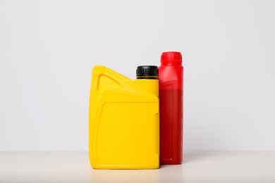 Photo of Motor oil in different canisters on table against white background