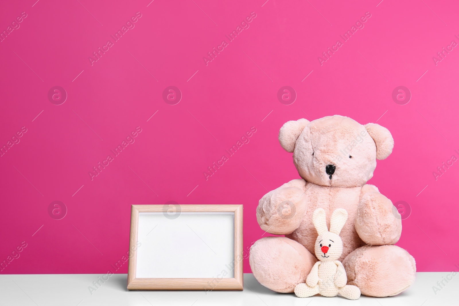 Photo of Photo frame and adorable toys on table against color background, space for text. Child room elements