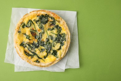 Photo of Delicious pie with spinach on green background, top view