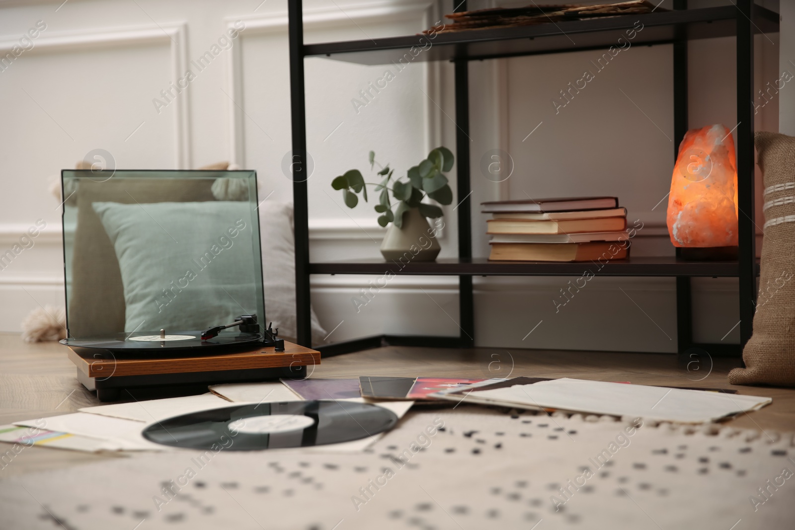 Photo of Stylish turntable with vinyl records on floor indoors