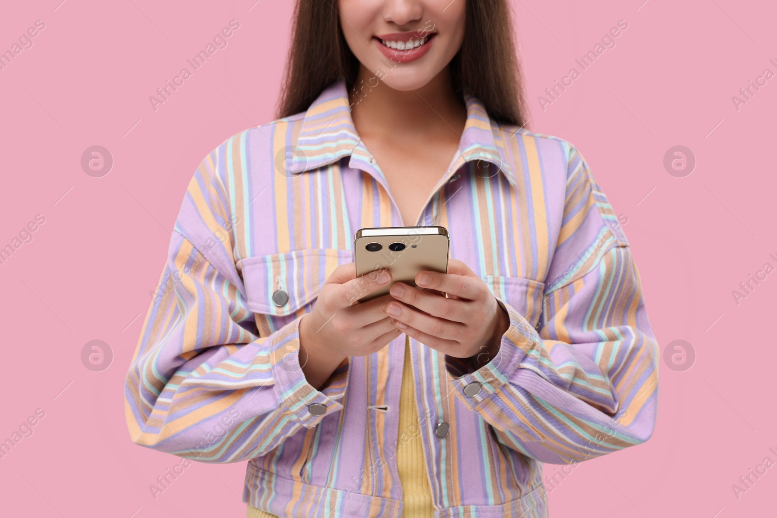 Photo of Woman sending message via smartphone on pink background, closeup