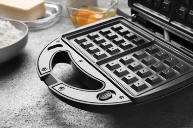 Modern electric waffle maker on grey table, closeup