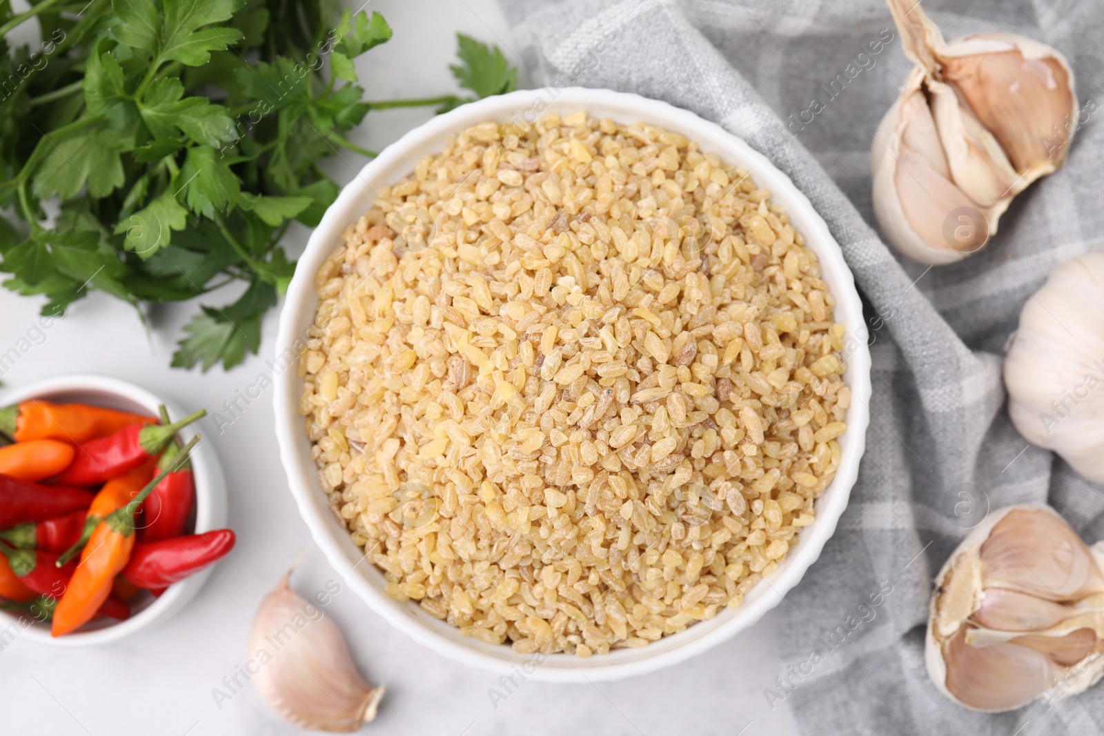 Photo of Raw bulgur in bowl and spices on table, flat lay