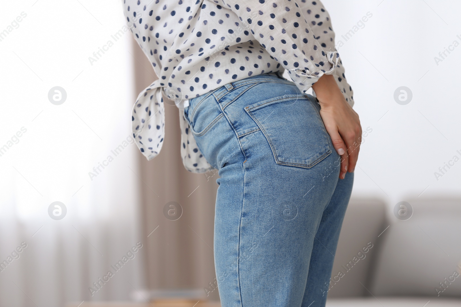 Photo of Young woman suffering from hemorrhoid at home, closeup