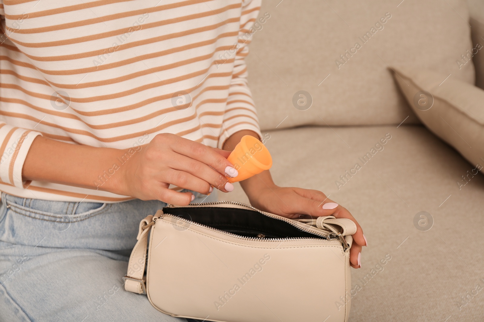 Photo of Woman putting menstrual cup into purse at home, closeup