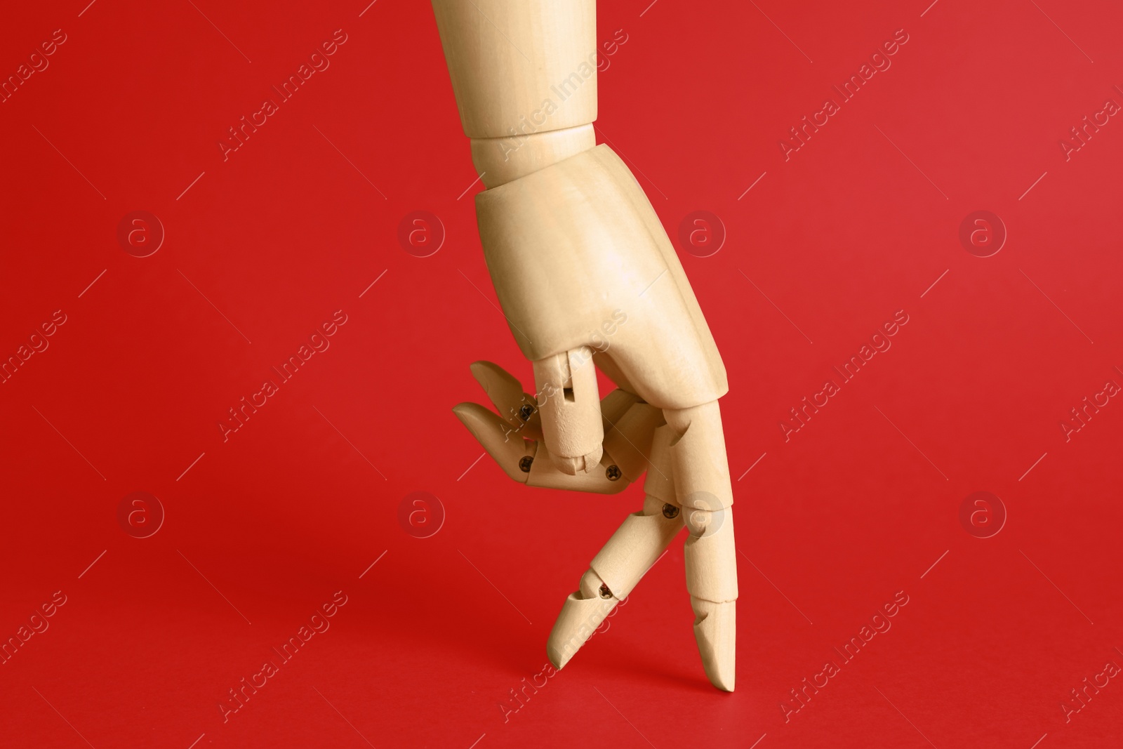 Photo of Wooden hand model on red background. Mannequin part
