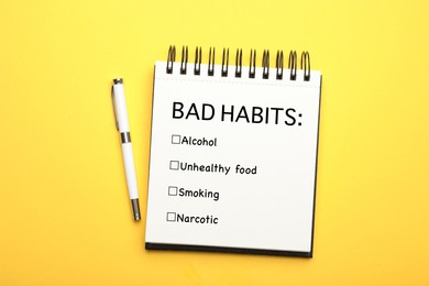 Image of Notebook with list of bad habits and pen on yellow background, top view. Change your lifestyle