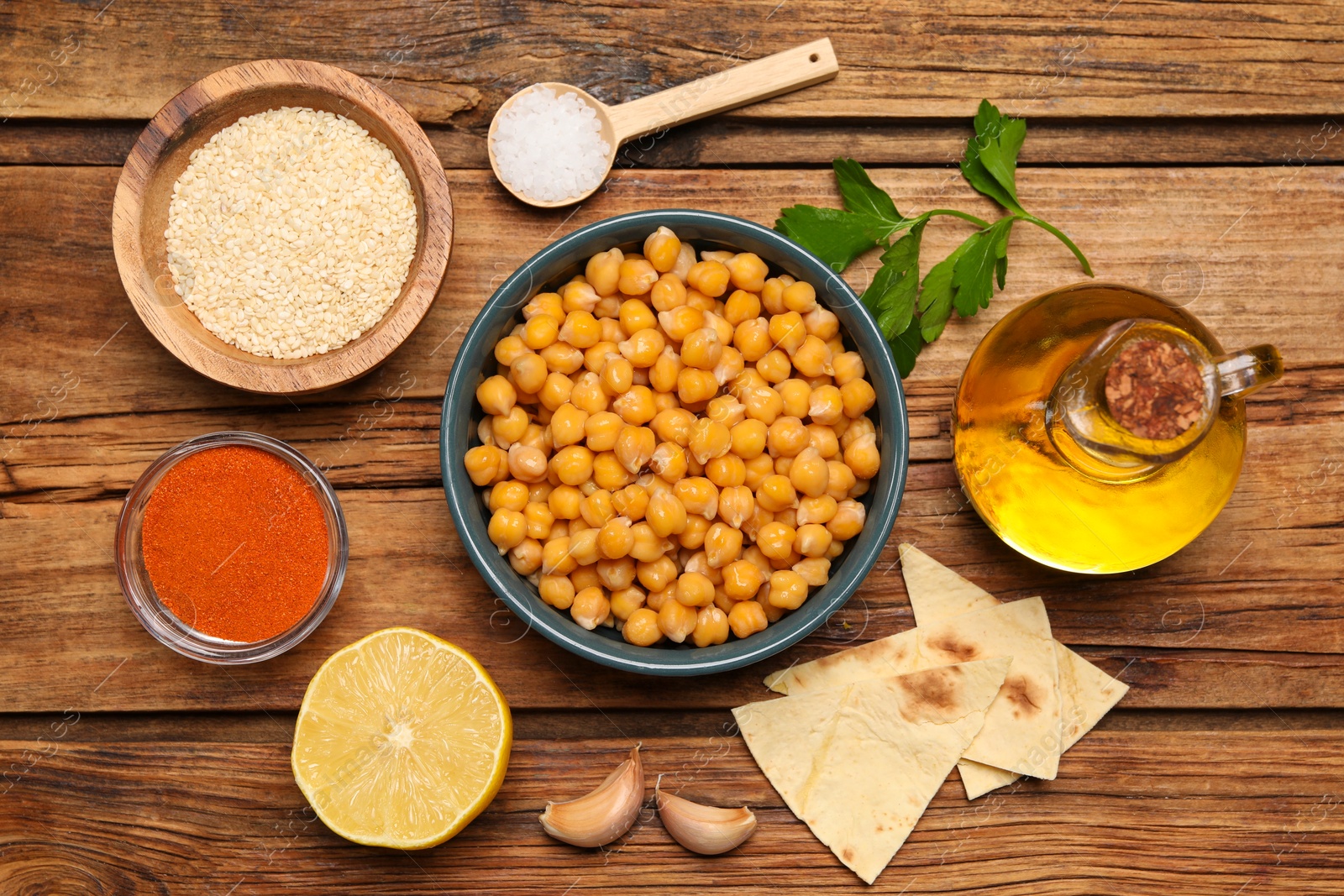 Photo of Delicious chickpeas and different ingredients on wooden table, flat lay. Cooking hummus