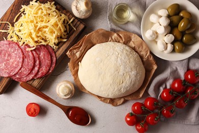 Photo of Pizza dough and products on gray textured table, flat lay