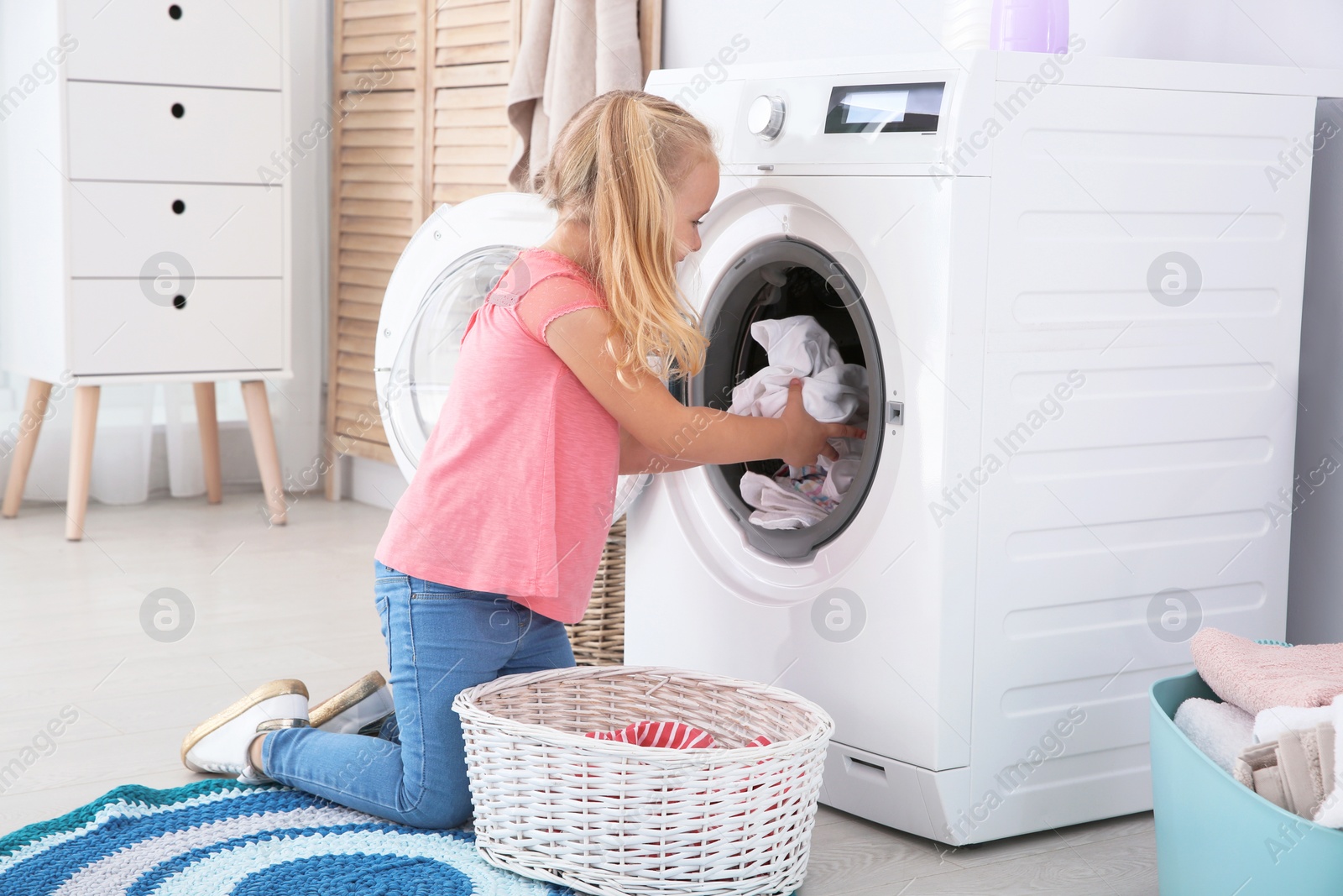 Photo of Adorable little girl doing laundry at home