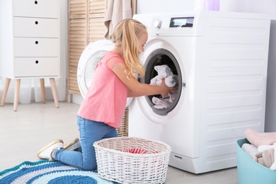 Adorable little girl doing laundry at home