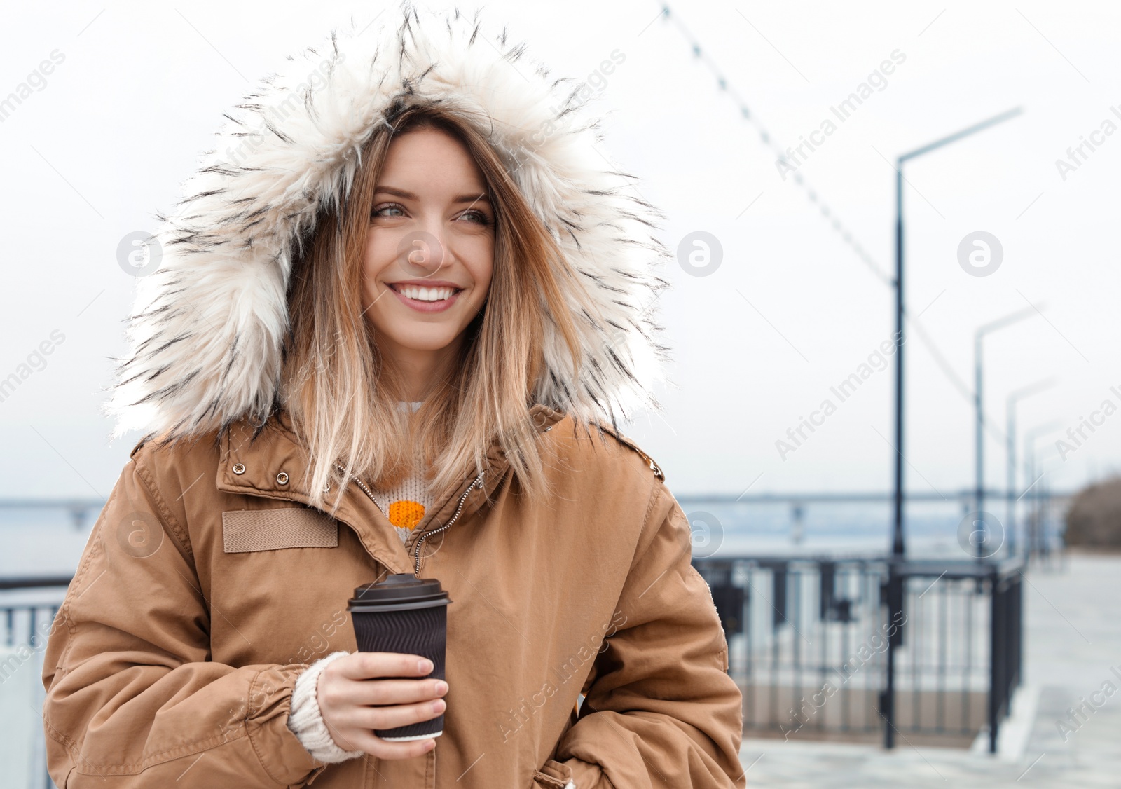 Photo of Young woman with cup of coffee walking outdoors. Space for text