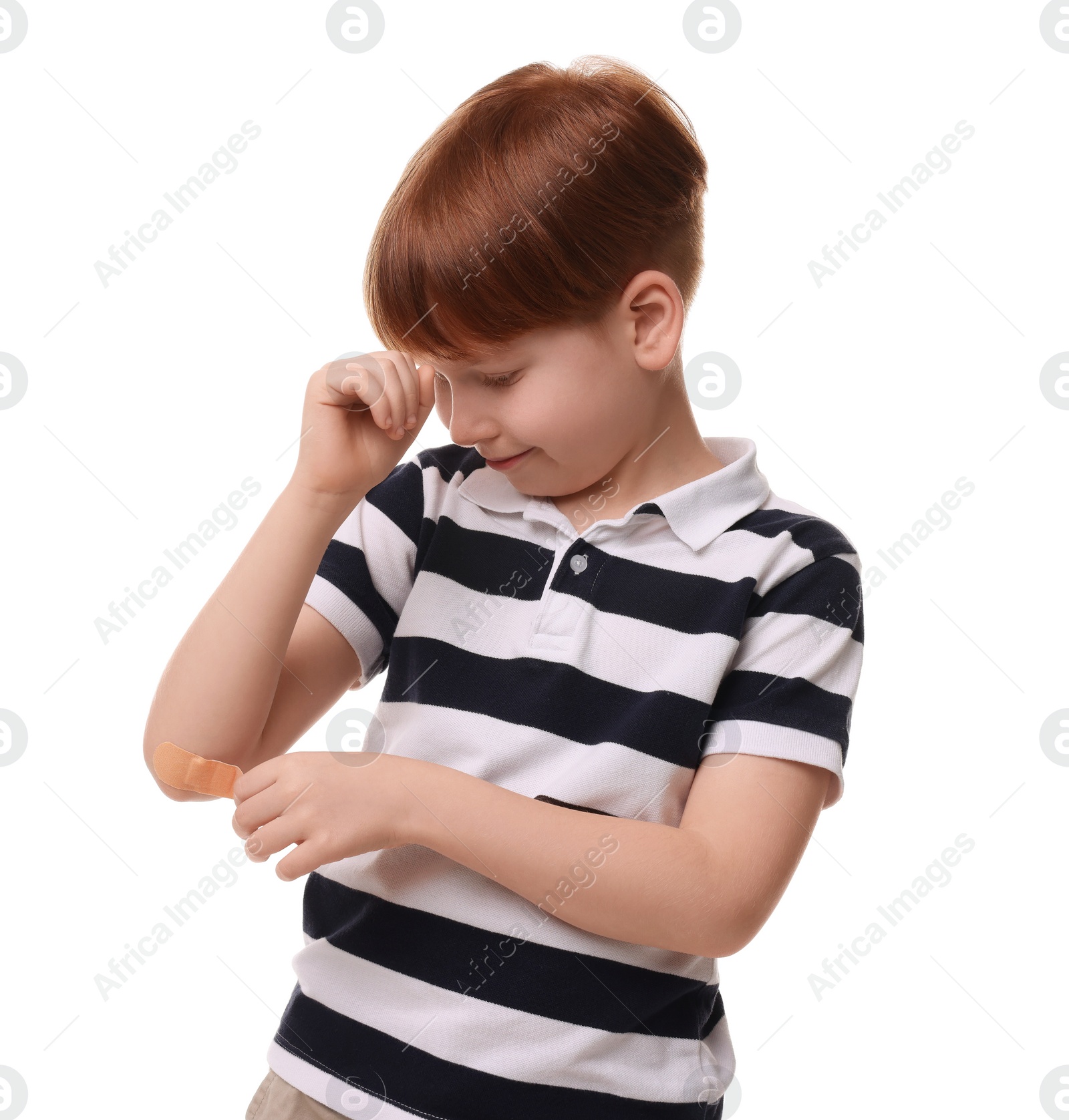 Photo of Little boy putting sticking plaster onto elbow on white background