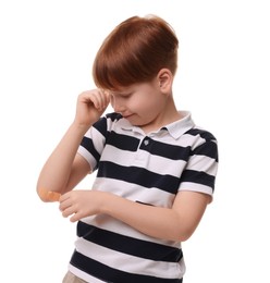 Little boy putting sticking plaster onto elbow on white background