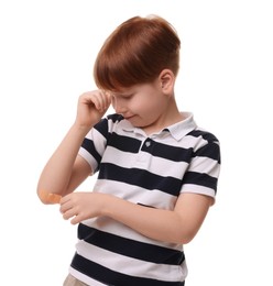 Photo of Little boy putting sticking plaster onto elbow on white background