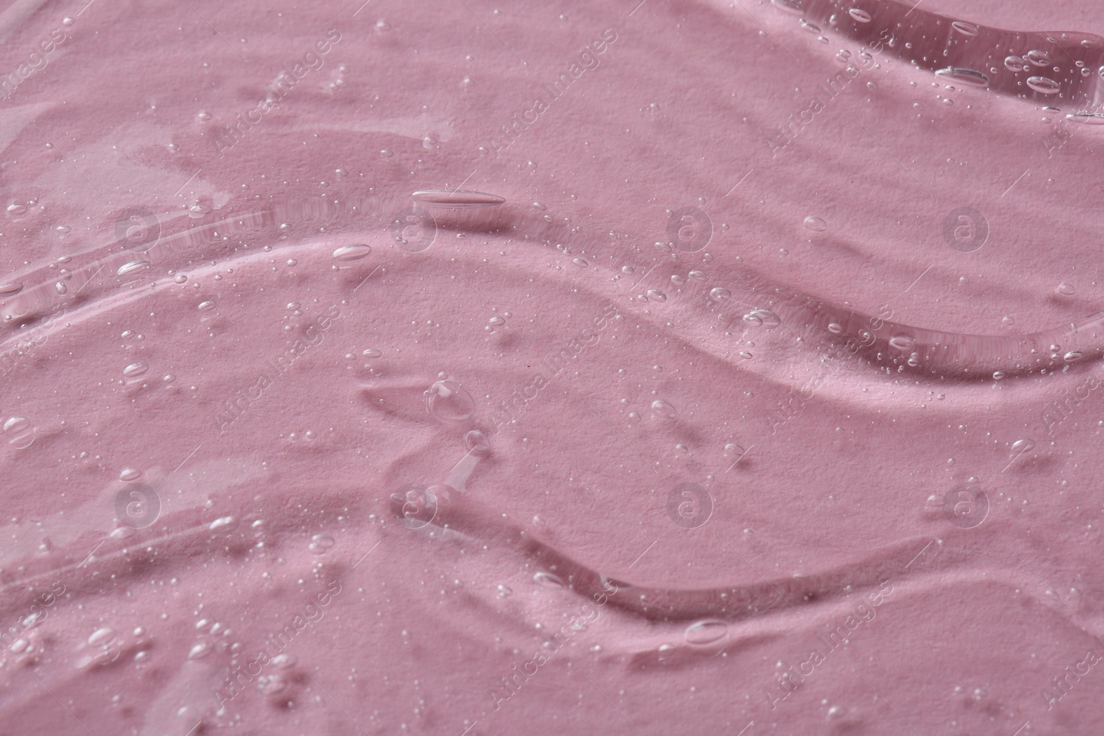 Photo of Clear cosmetic serum on pink background, macro view