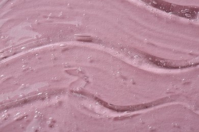 Clear cosmetic serum on pink background, macro view