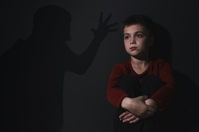 Image of Child abuse. Father yelling at his son. Shadow of man on wall