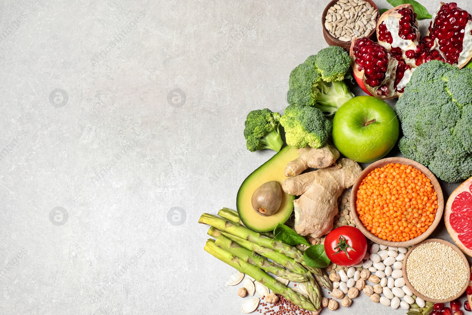 Photo of Fresh vegetables, fruits and seeds on grey table, flat lay. Space for text