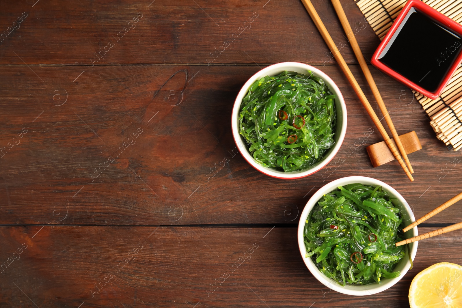 Photo of Japanese seaweed salad served on wooden table, flat lay. Space for text