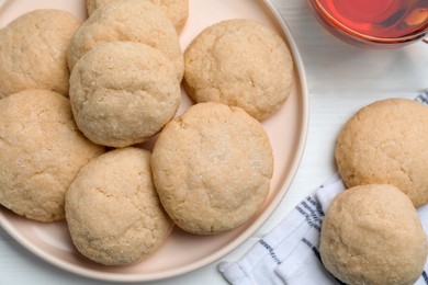 Delicious sugar cookies and cup of tea on white wooden table, flat lay