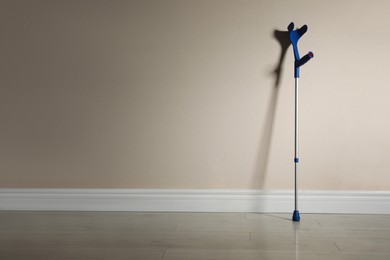 Photo of Elbow crutch near color wall. Space for text