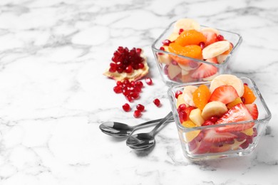 Photo of Delicious fresh fruit salad on white marble table, space for text