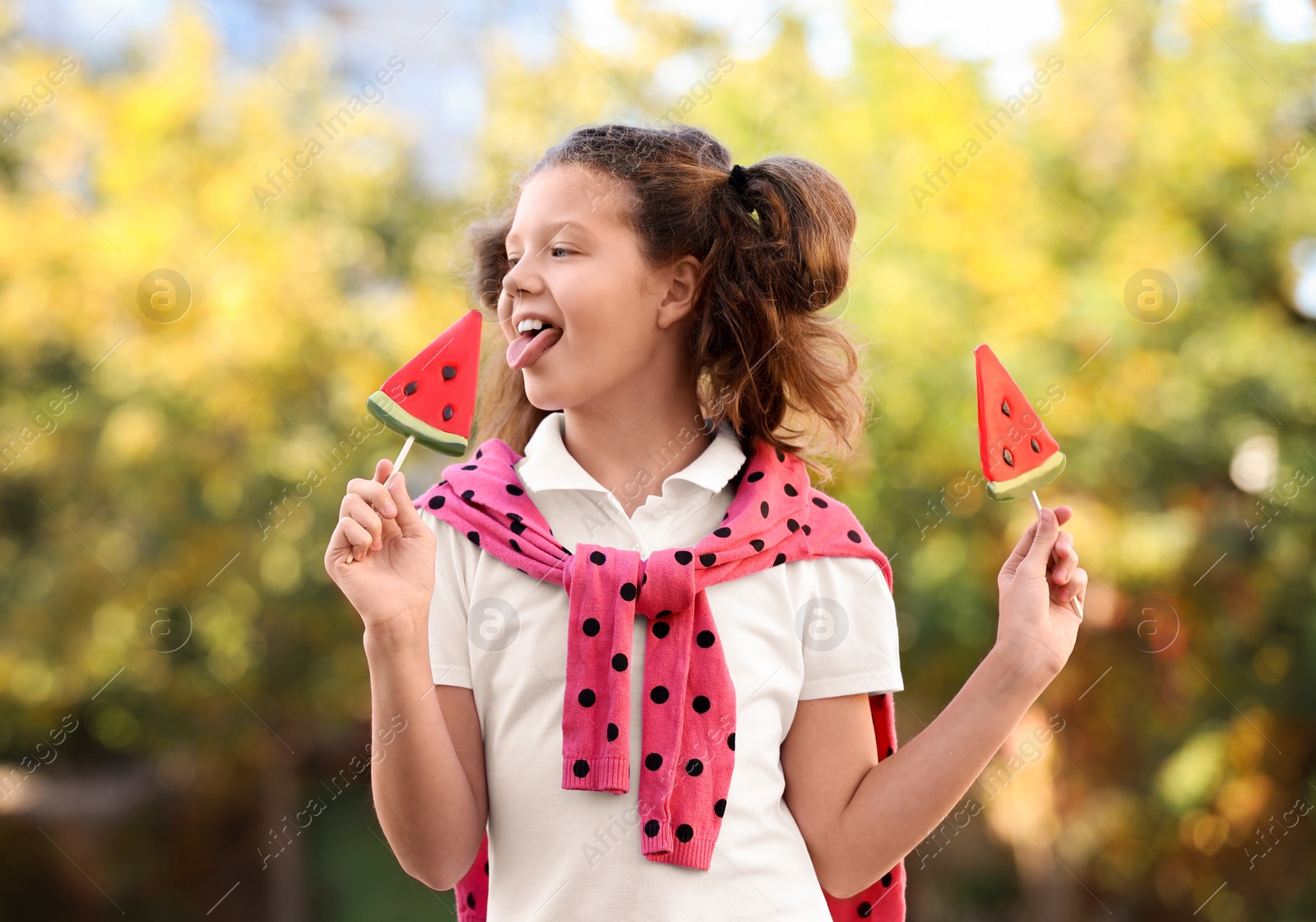 Photo of Cute little girl with tasty candies outdoors