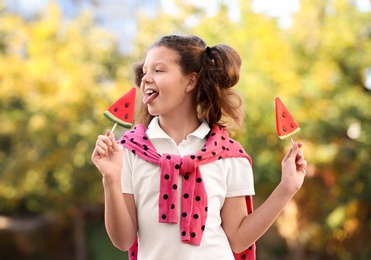 Cute little girl with tasty candies outdoors