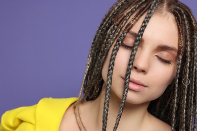 Photo of Beautiful woman with long african braids on purple background, closeup. Space for text
