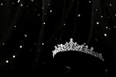 Photo of Beautiful silver tiara with diamonds on dark mirror surface. Space for text