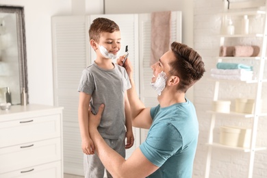 Photo of Dad pretending to shave his little son in bathroom