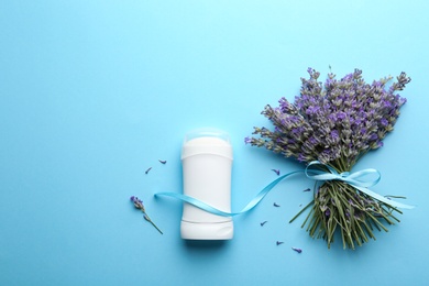 Photo of Female deodorant and lavender flowers on light blue background, flat lay