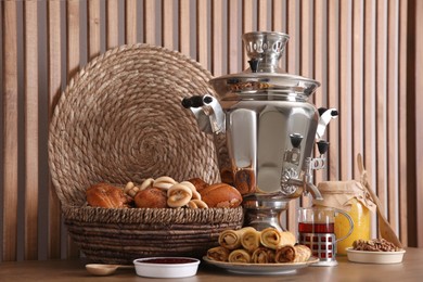 Photo of Traditional Russian samovar with treats on wooden table