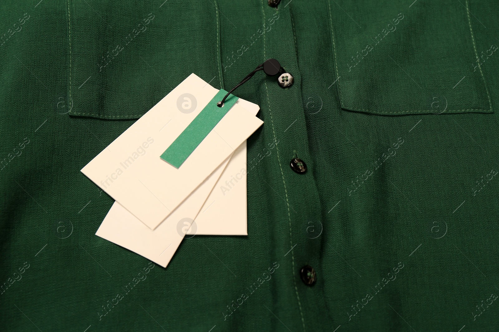 Photo of Blank white tags on green shirt. Space for text