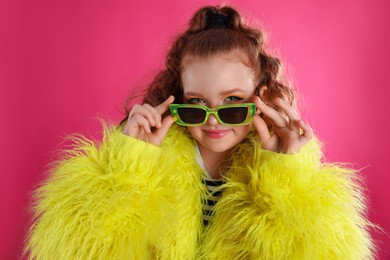 Photo of Cute indie girl with sunglasses on pink background