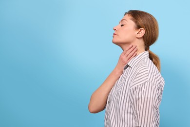 Photo of Woman suffering from sore throat on light blue background. Space for text