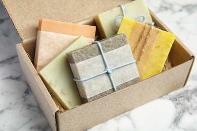 Photo of Cardboard box with different handmade soap bars on table
