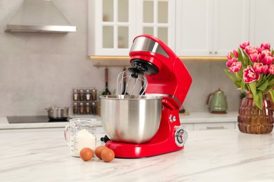 Photo of Modern red stand mixer, eggs and container with flour on white marble table in kitchen