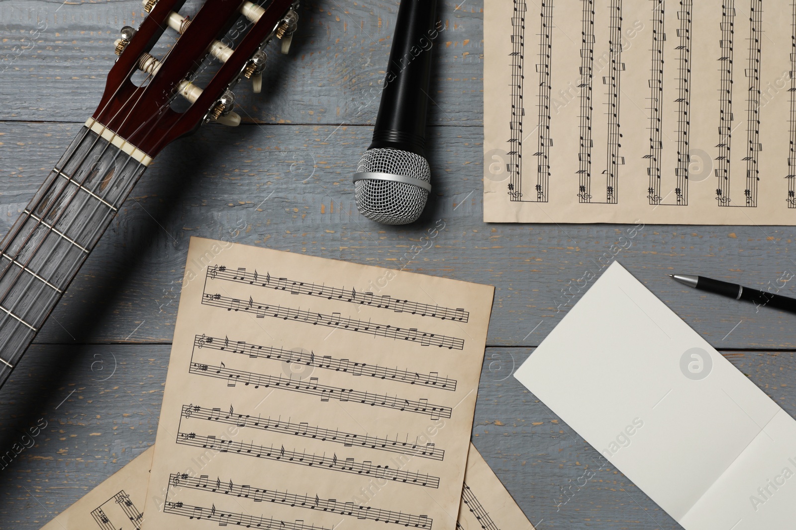 Photo of Composition with guitar and music notations on grey wooden table, flat lay