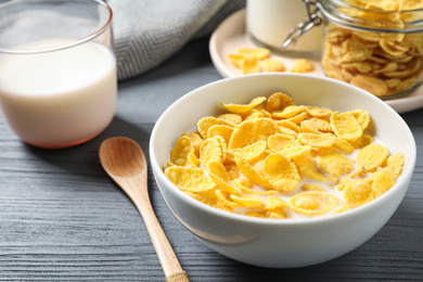 Tasty crispy corn flakes with milk on grey wooden table