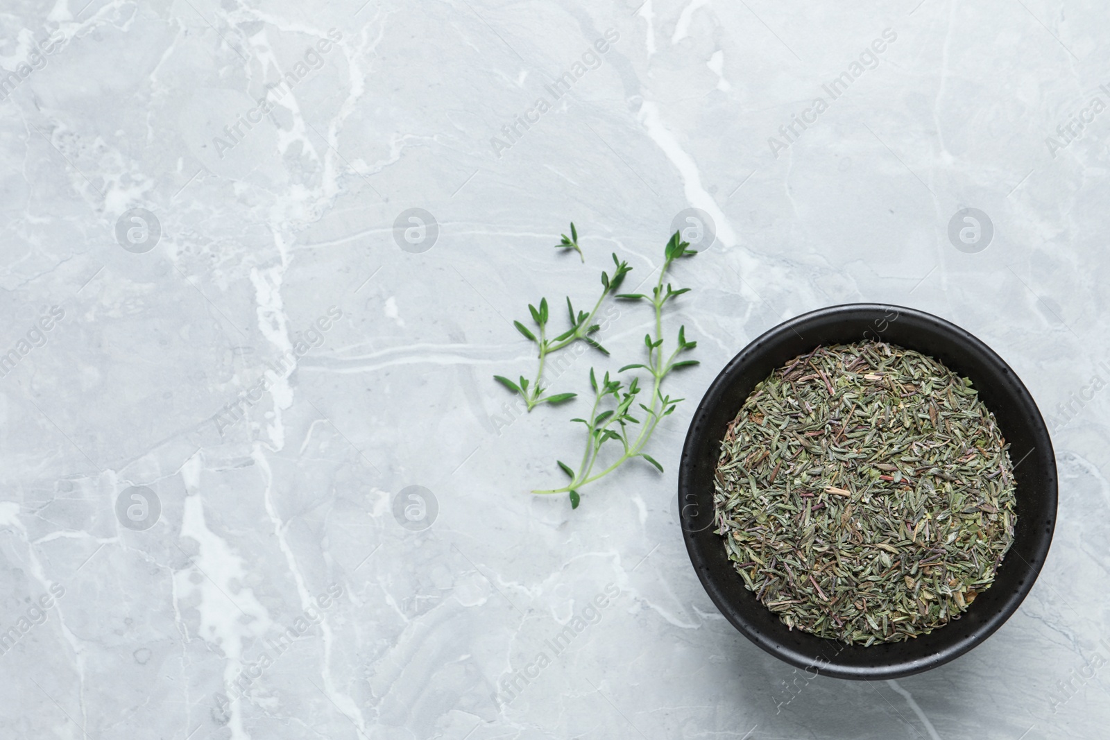 Photo of Bowl with dried thyme and fresh twigs on light table, flat lay. Space for text