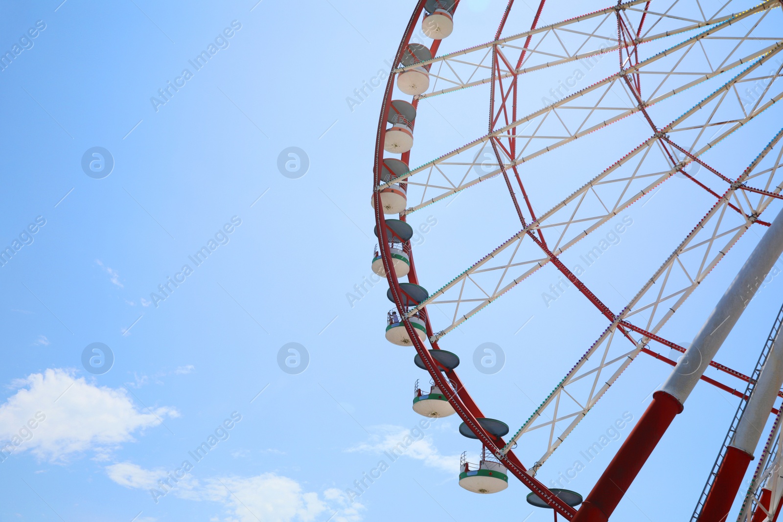 Photo of Beautiful large Ferris wheel against blue sky with clouds on sunny day