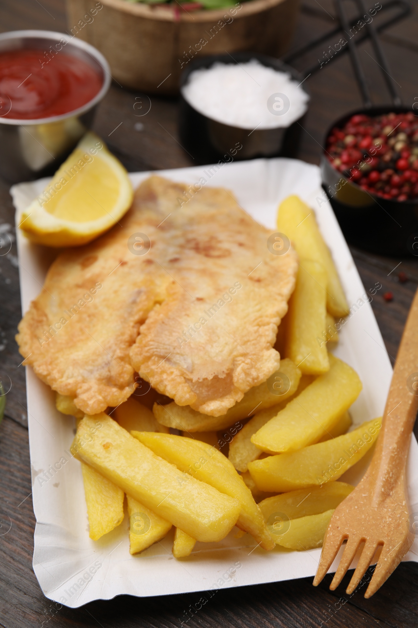 Photo of Delicious fish and chips served on wooden table, closeup