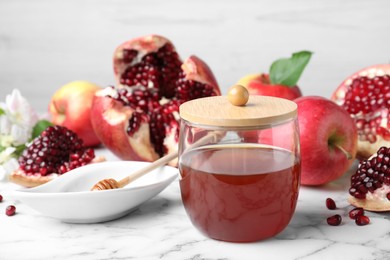Photo of Honey, pomegranate and apples on white marble table. Rosh Hashana holiday